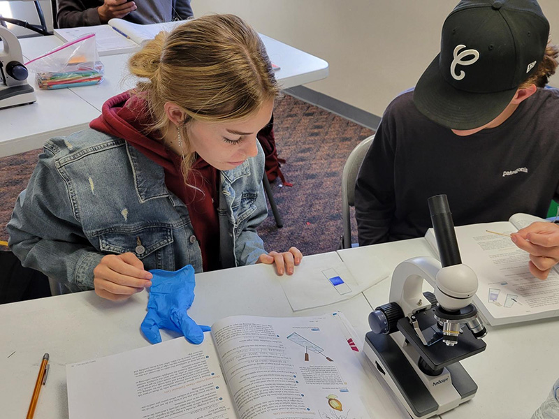 Two students engaged in a science moment using a microscope