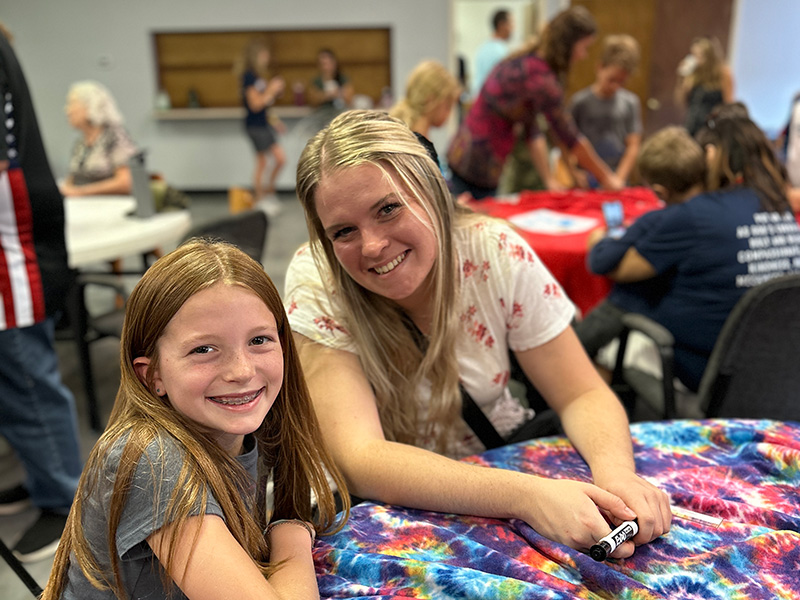 Teacher and student smiling with classroom activities going on around them